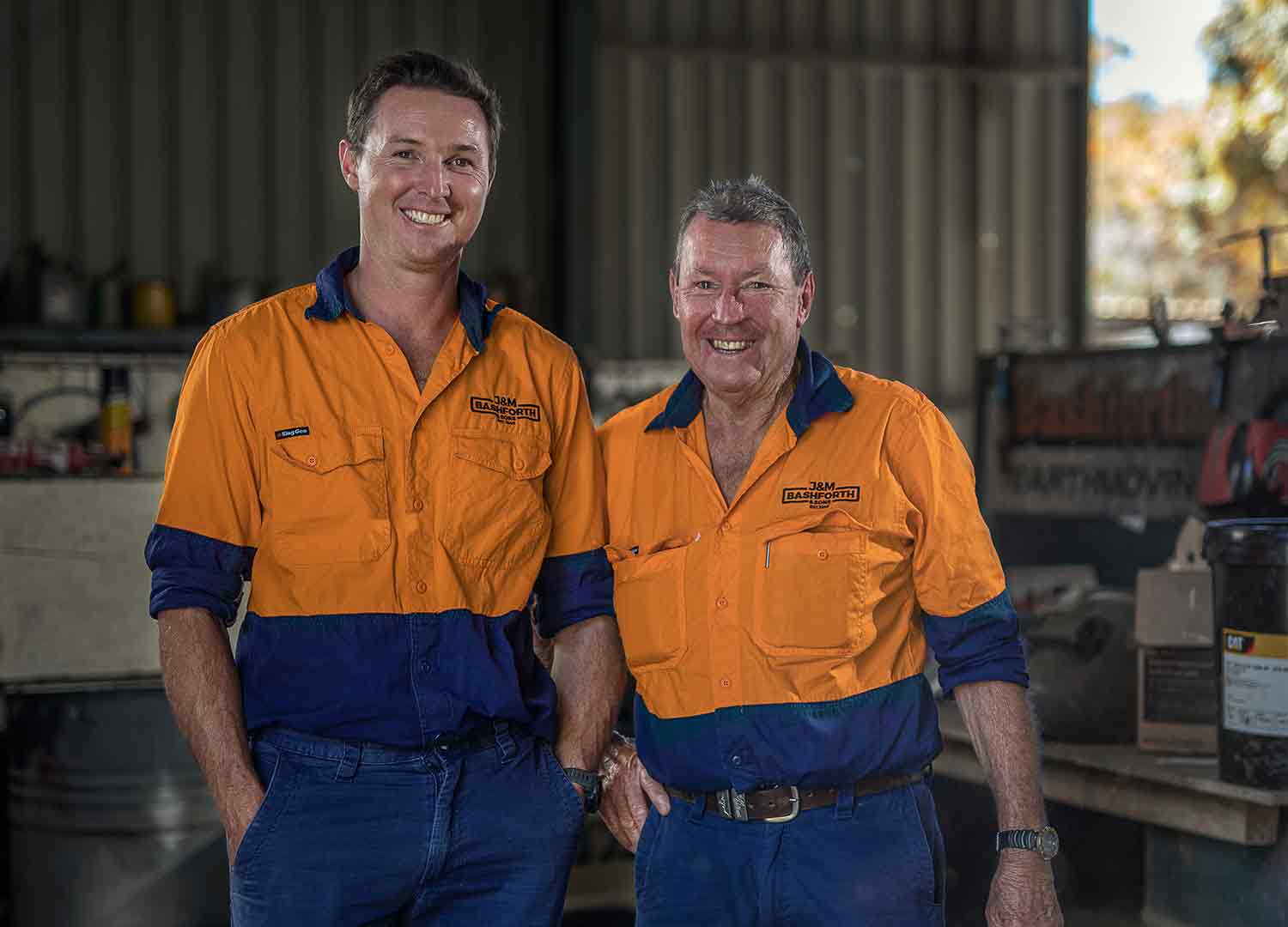 Luke and John Bashforth standing side by side in a shed